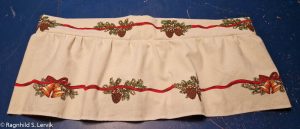 Løpegang og kappe sydd sammen, både løpegangen og kappen har girlander på langs.